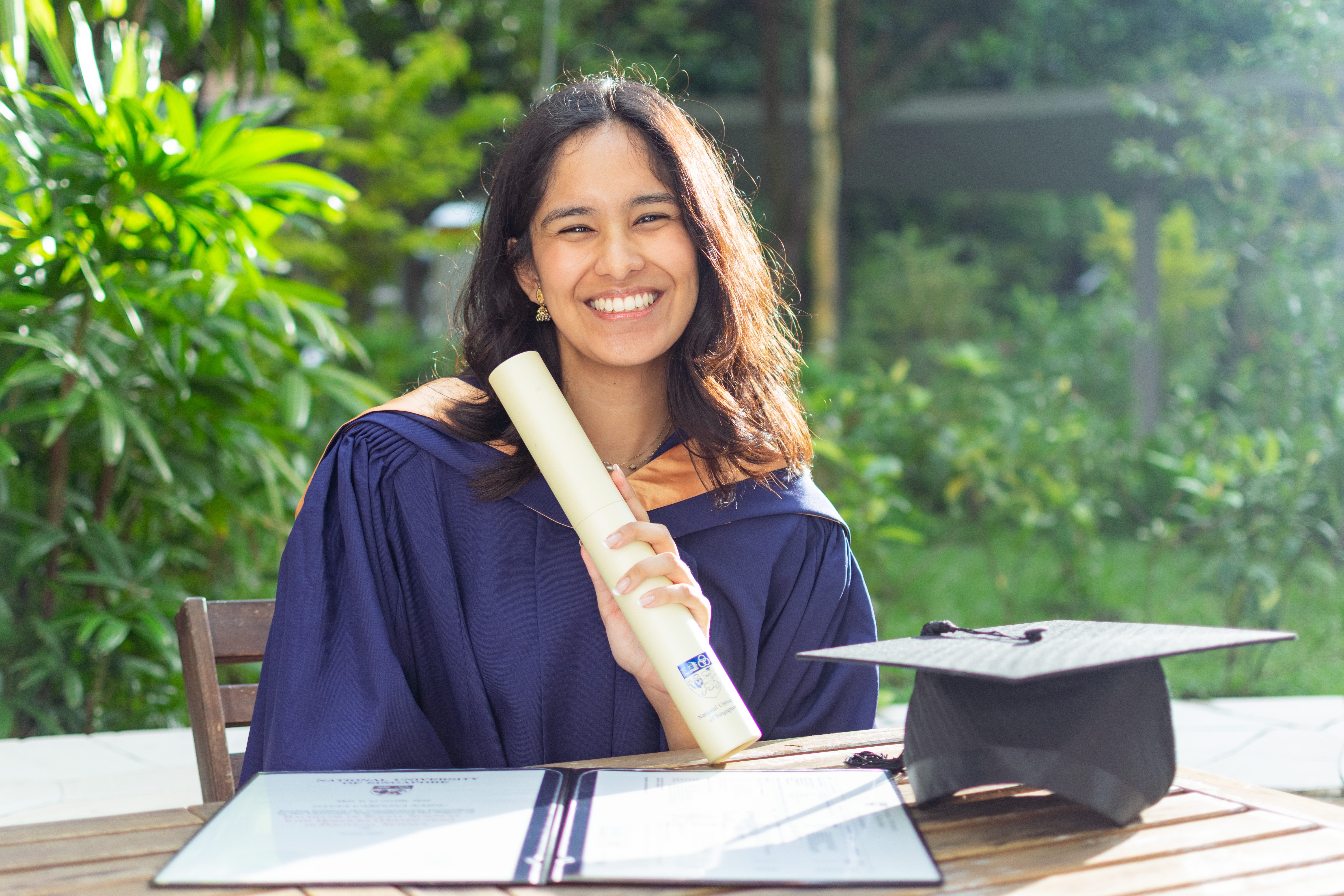 Graduate holding cap and gown in bright daylight